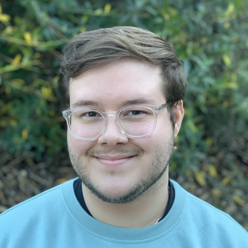 headshot of man with glasses and brown hair with blue shirt 