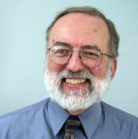 professional photo os man with glasses and gray beard smiling for the camera